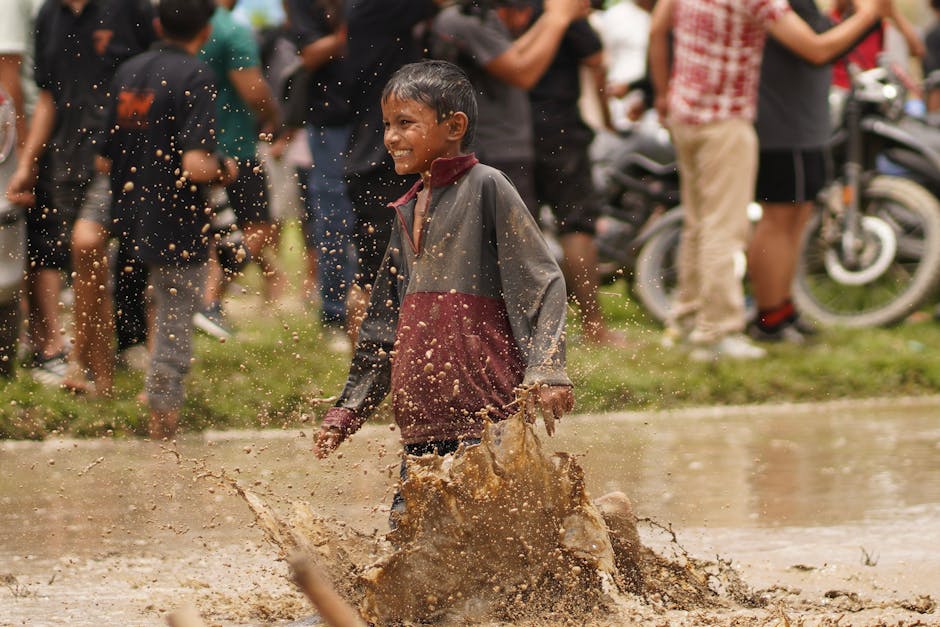 A child joyfully splashes in muddy water during an outdoor community event in Bagmati Province, Nepal.